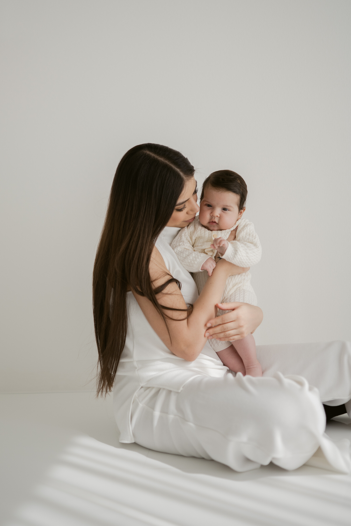 Motherhood Fotografie in Freiburg – inniger Moment zwischen Mama und Baby im monochromen Tageslichtstudio