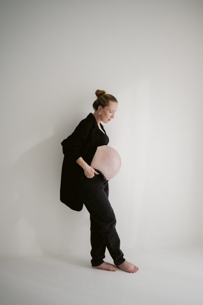 Schwangerschaftsfotografie in Freiburg – zeitlose Studioaufnahme im reduzierten monochromen Raum. mit klarer Haltung und ruhiger Präsenz
