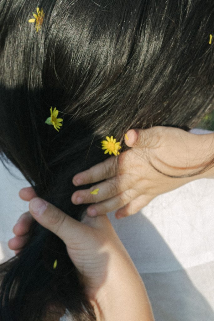 Detailaufnahme einer Mutter mit kleinen gelben Blumen im Haar